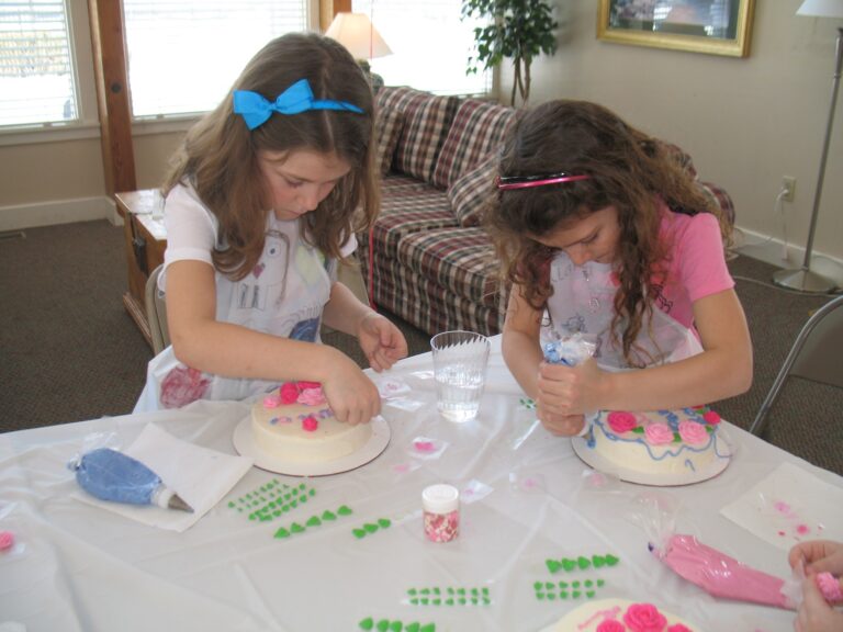 Two girls decorating their cakes