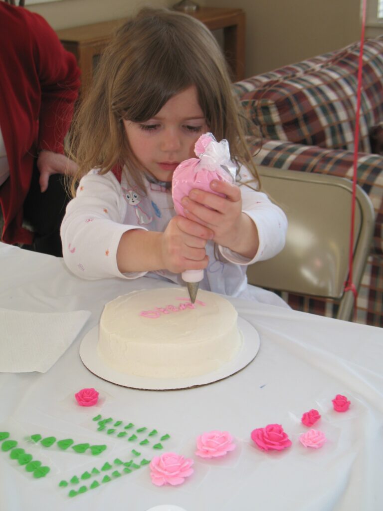 Sugar Whimzy decorating Party with small girl piping frosting onto her cake