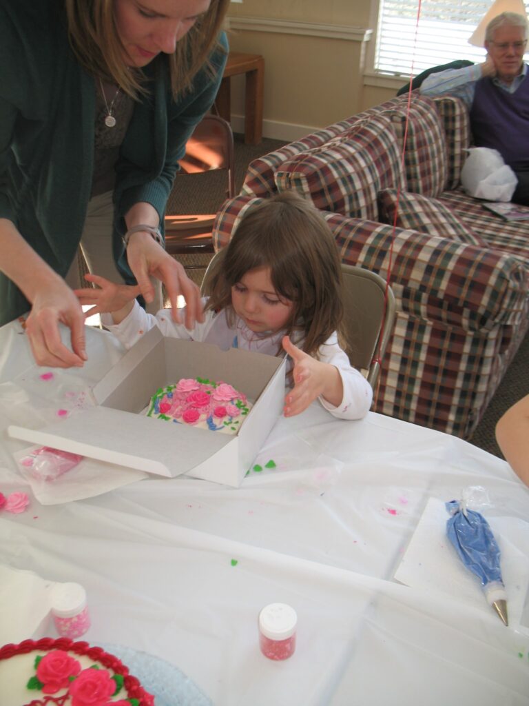 small girl boxing up the cake she decorated