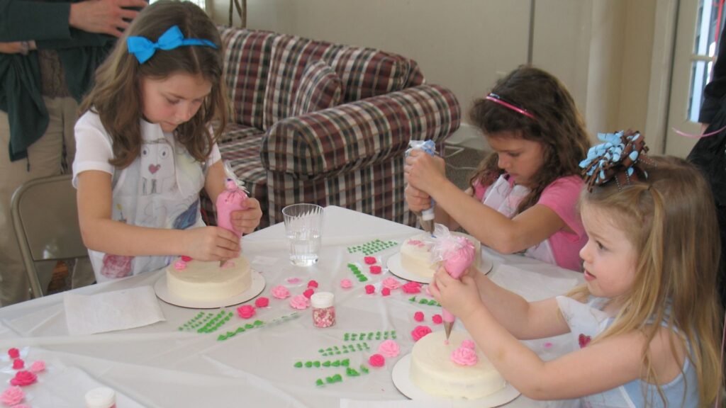 small girls decorating cakes