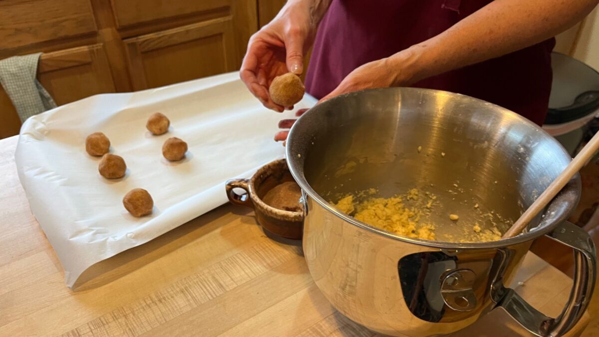 A bowl of cookie dough, with allergy friendly ingredients, and a cookie sheet with parchment on it.