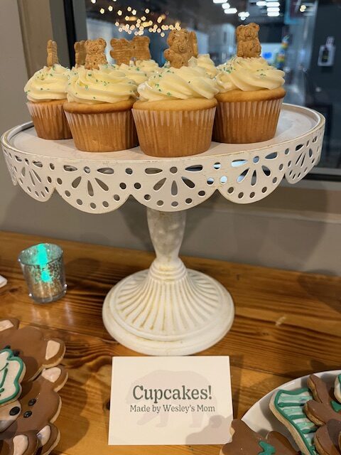 White iced Cupcakes with a graham bear sticking out of the top on a white stand